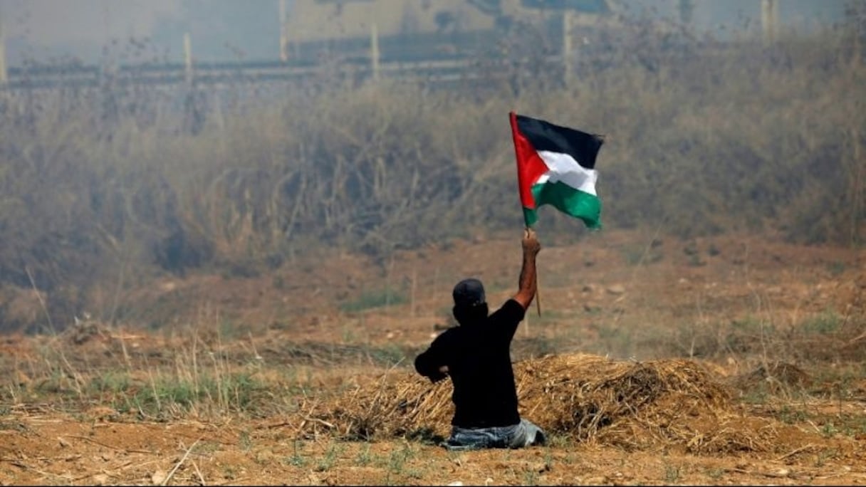 Ibrahim Abou Thouraya brandissant un drapeau palestinien lors d'affrontements avec les soldats israéliens dans la bande de Gaza, le 19 mai 2017.
