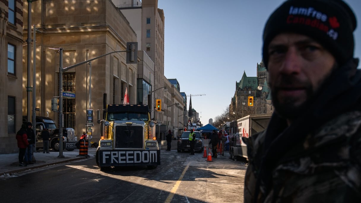 Un manifestant regarde un chauffeur déplacer son véhicule dans la zone centrale de la rue Wellington, au cours d'une manifestation de camionneurs contre les mesures restrictives dues à la pandémie, devant le Parlement du Canada, à Ottawa, le 14 février 2022.
