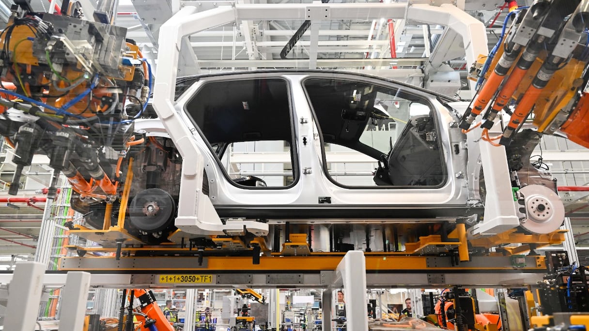 Des robots travaillent sur la chaîne de montage d'une voiture électrique Volkswagen ID.4, au cours du lancement de sa production sur le site du constructeur automobile allemand Volkswagen à Emden, dans le nord de l'Allemagne, le 20 mai 2022.
