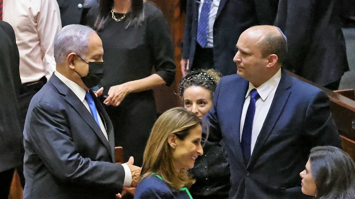 Le Premier ministre israélien sortant Benjamin Netanyahu serre la main de son successeur, le Premier ministre entrant Naftali Bennett, après une session extraordinaire pour le vote d'un nouveau gouvernement à la Knesset, à Jérusalem, le 13 juin 2021. 
