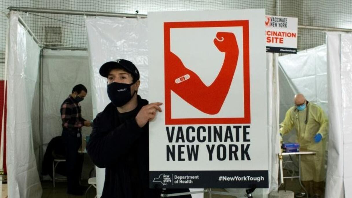 Un travailleur de santé porte une affiche lors de l'ouverture d'un centre de vaccination à Harlem, New York, le 15 janvier 2021. 
