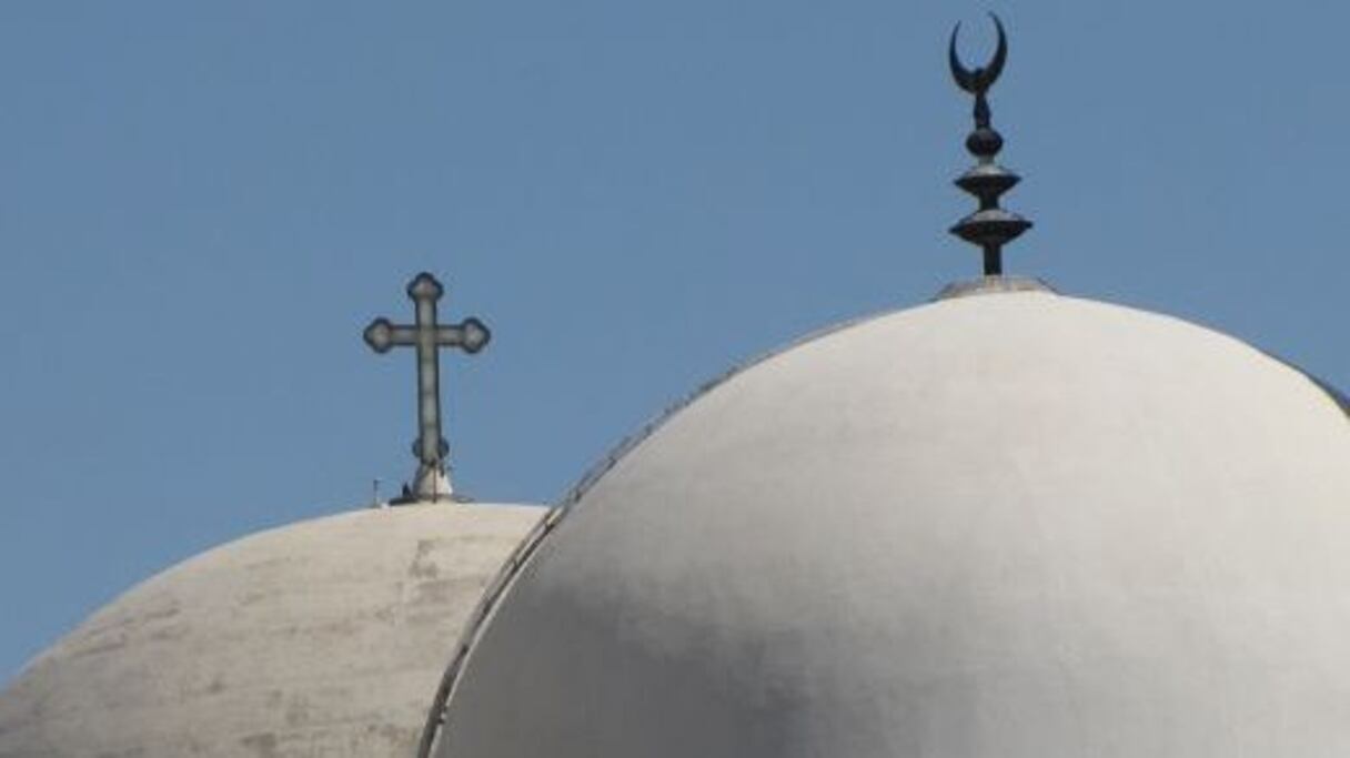 Dômes de deux édifices religieux, l'un surmonté d'une croix, symbole du christianisme, l'autre d'un croissant, symbole de l'islam. 
