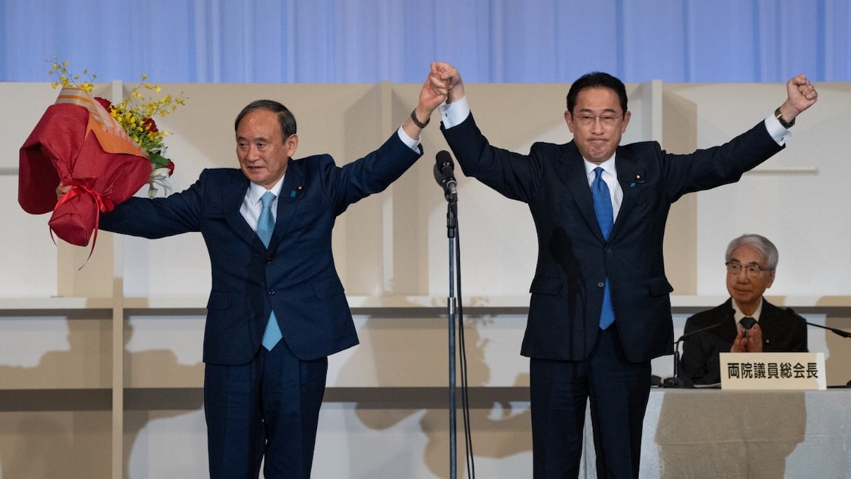 Candidat du Parti libéral-démocrate (LDP), Fumio Kishida, ancien ministre des Affaires étrangères, célèbre sa victoire avec le Premier ministre sortant Yoshihide Suga (à gauche) après avoir été élu président du parti, à Tokyo, le 29 septembre 2021.
