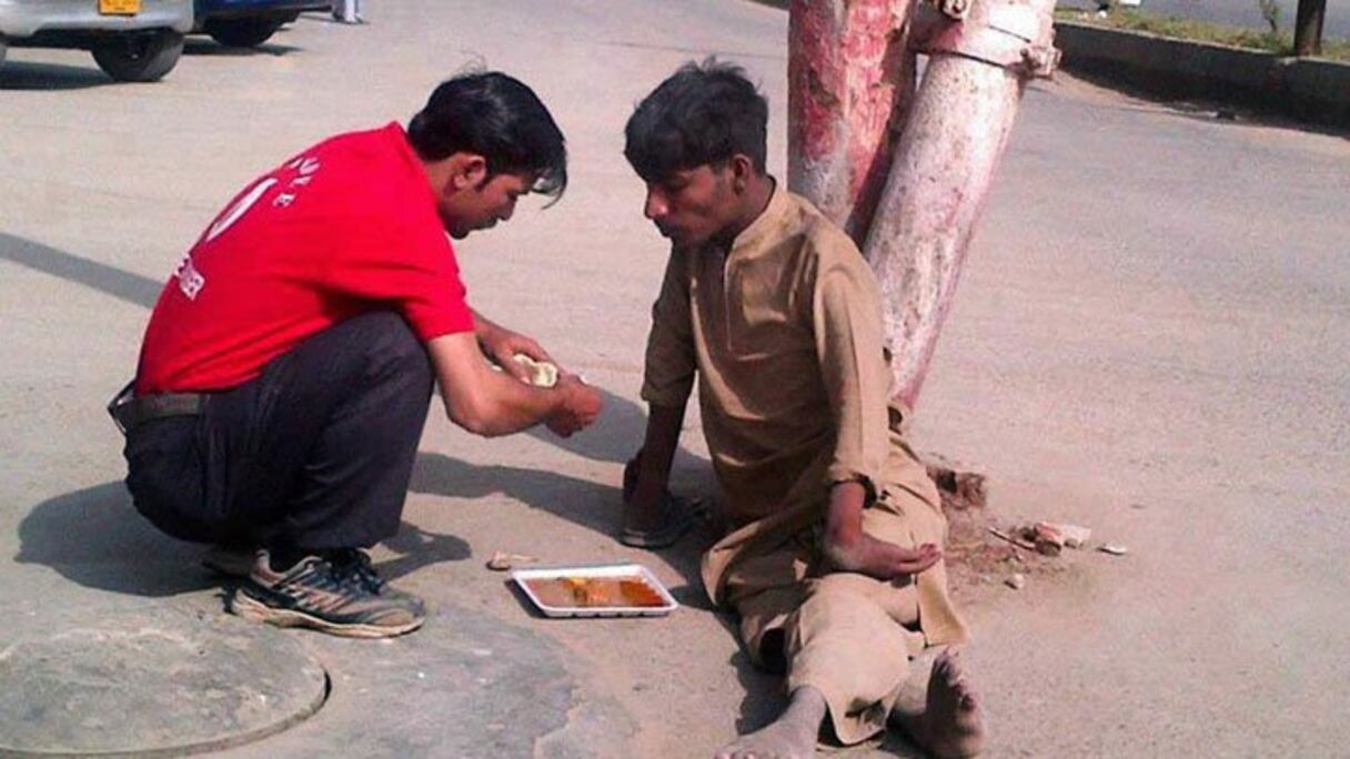 Un commerçant quitte sa boutique pour nourrir un sans-abri handicapé. 
