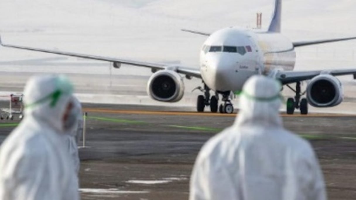 Des équipes sanitaires sur le tarmac d'un aéroport. 
