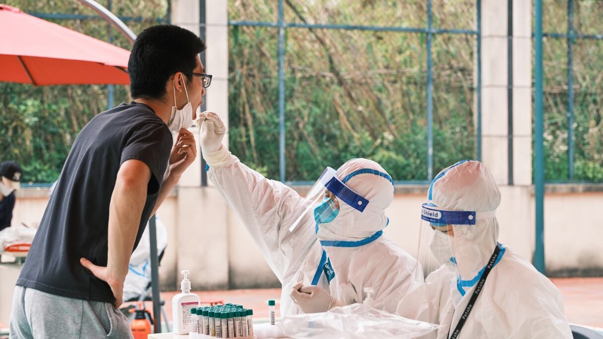 Un agent de santé portant un équipement de protection individuelle effectue un test sur écouvillon pour détecter le Covid-19 dans un complexe, lors d'un confinement dans le district de Pudong, à Shanghai, le 19 avril 2022.
