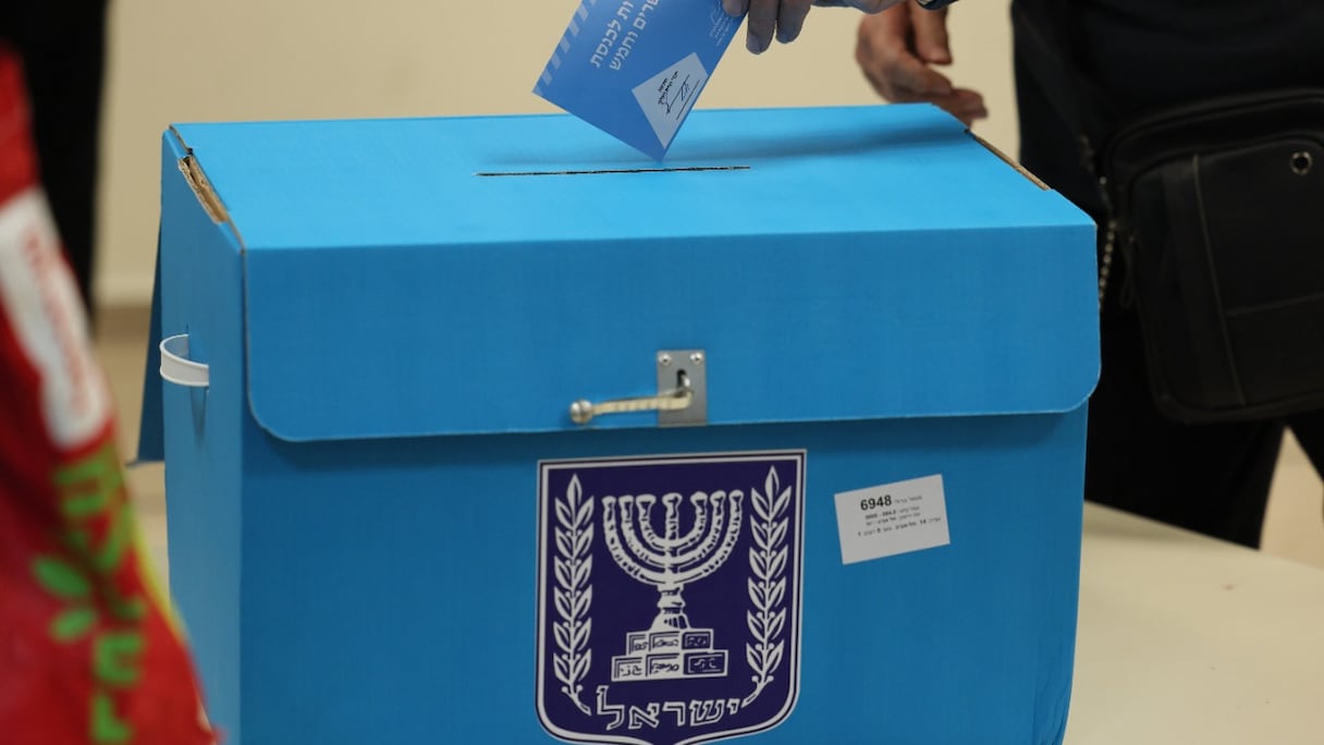 Un électeur israélien s'apprête à glisser son bulletin de vote dans une urne, au cours de la cinquième élection israélienne en moins de quatre ans, dans un bureau de vote de Tel Aviv, le 1er novembre 2022.
