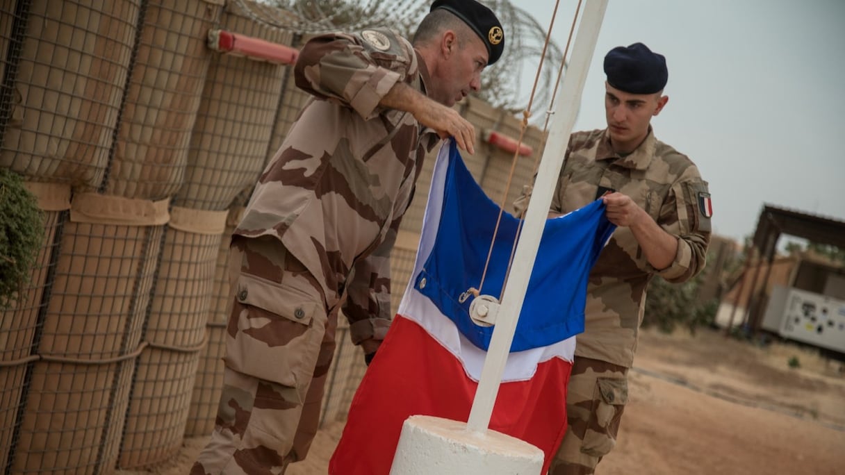 Des soldats de l'opération Barkhane pliant le drapeau français après qu'il a été retiré du mât de la base militaire de Barkhane lors d'une cérémonie de passation de pouvoir à l'armée malienne à Tombouctou, le 14 décembre 2021.
