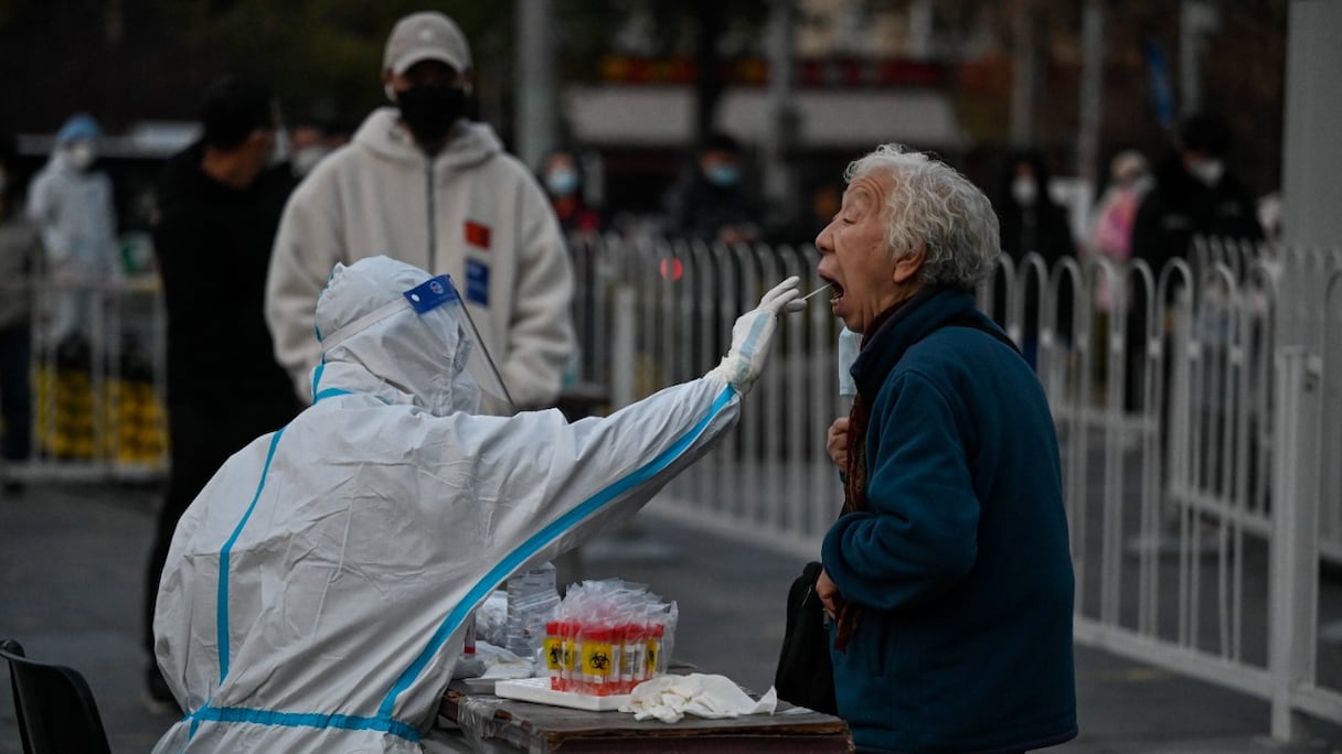 Un agent de santé prélève sur une femme un échantillon de salive pour un test du Covid-19, à Pékin le 22 novembre 2022.
