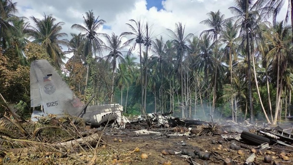 De la fumée s'échappe de l'épave d'un avion de transport Philippine Airforce C-130 après son crash près de l'aéroport de la ville de Jolo, dans la province de Sulu, sur l'île méridionale de Mindanao, le 4 juillet 2021. 
