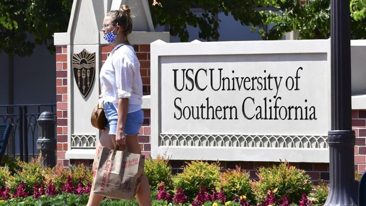 Une femme passe devant un panneau de l'Université de Californie du Sud à Los Angeles, en Californie, qui a accepté de payer plus d'un milliard de dollars à des centaines de victimes présumées d'abus sexuels du gynécologue du campus, George Tyndall (photo du 25 août 2021).

