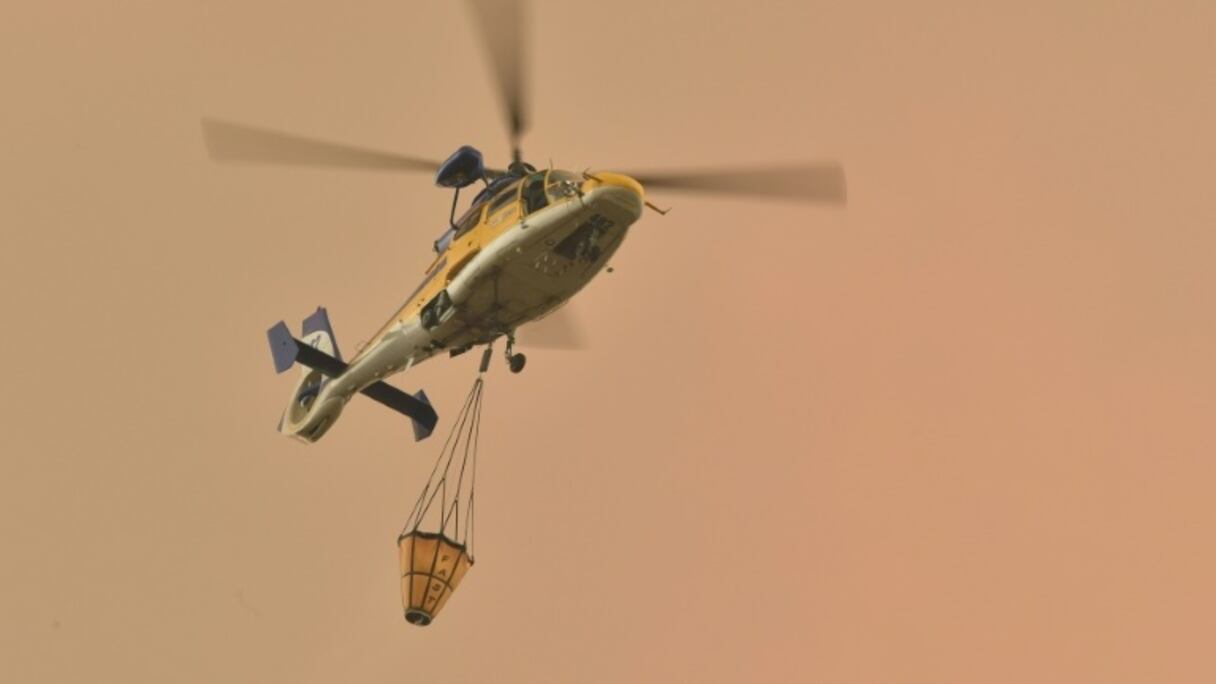 Un hélicoptère va larguer une charge d'eau sur un feu de forêt à Bargo, le 21 décembre 2019 en Australie.
