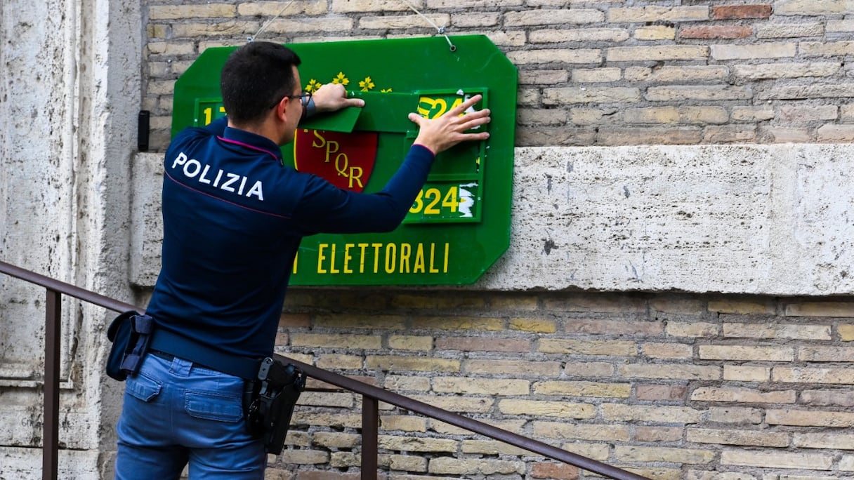 Un policier installe un panneau d'identification officiel le 24 septembre 2022 devant un bureau de vote à Rome, à la veille des élections législatives du pays.
