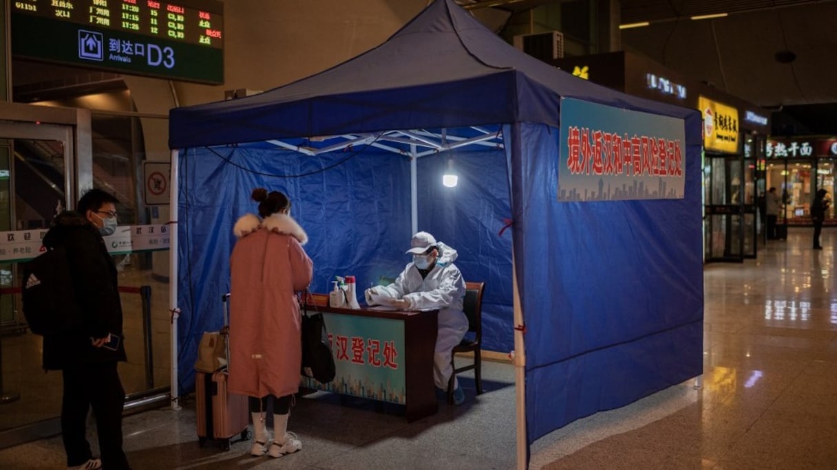 Des personnes enregistrent leur itinéraire de voyage à un portique de la principale gare de Wuhan, le 10 janvier 2021, à la veille du premier anniversaire de l'annonce par la Chine d'un premier décès dû au Covid-19.
