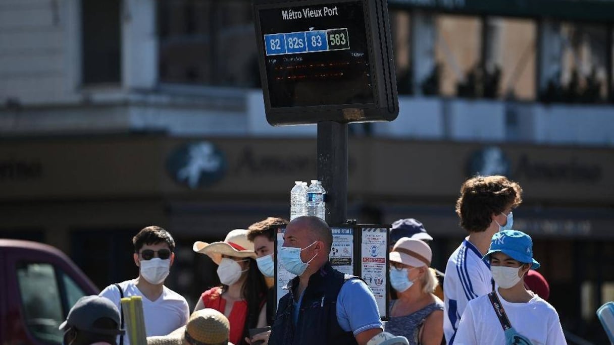 Des personnes portant des masques attendent à un arrêt de bus sur le Vieux Port, le 26 août 2020 à Marseille, dans le sud de la France. 
