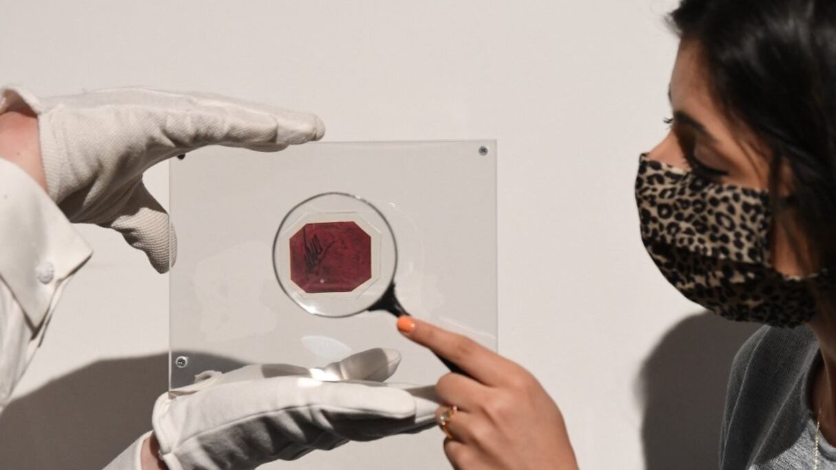 Un assistant de la maison de ventes Sotheby's pose avec l'unique One-Cent Magenta de Guyane britannique, lequel, selon de précédentes ventes, est le timbre unique le plus cher au monde, à Londres, le 28 avril 2021.
