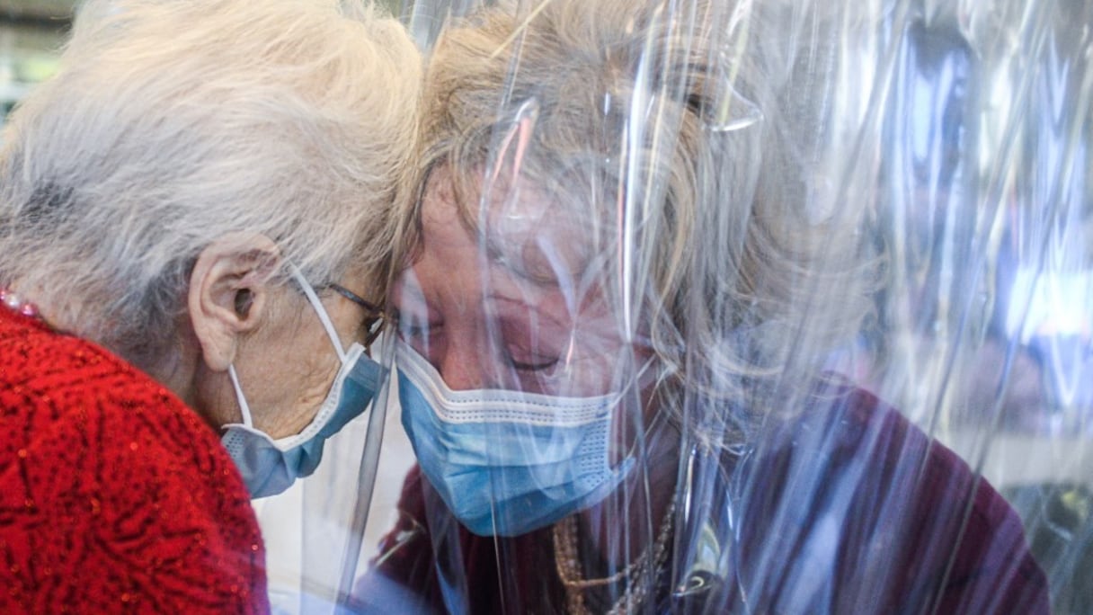 Une patiente atteinte du Covid-19 à Castelfranco Veneto, reçoit la visite de sa fille le 11 novembre 2020, et s'approche d'elle à travers un écran en plastique dans la "hug room" de cet établissement hospitalier près de Venise, en Italie.
