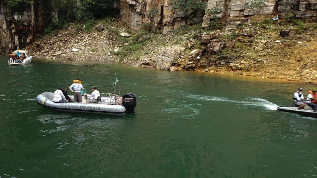 Des pompiers viennent au secours de touristes au cours d'une opération de sauvetage après la chute du pan d'une falaise sur des bateaux navigant dans un lac de l'Etat du Minas Gerais, au sud-est du Brésil, le 8 janvier 2022.