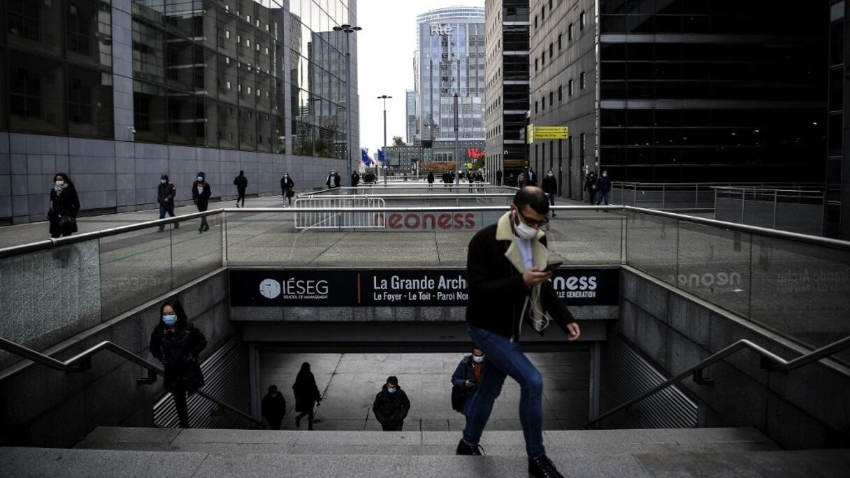 Un homme masqué sort du métro dans le quartier d'affaires de La Défense, à Paris, au matin du 16 octobre 2020, et s'apprête à rejoindre son lieu de travail. 
