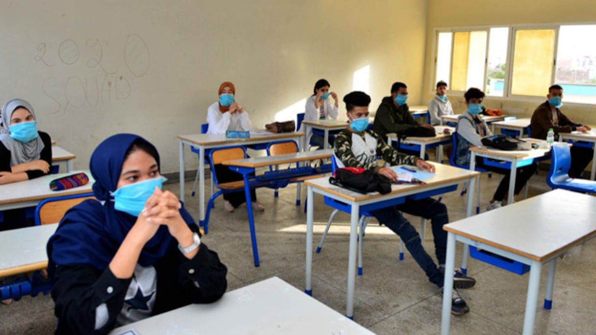 Port du masque et distanciation physique pour des élèves en cours dans une salle de classe de l'enseignement secondaire. 
