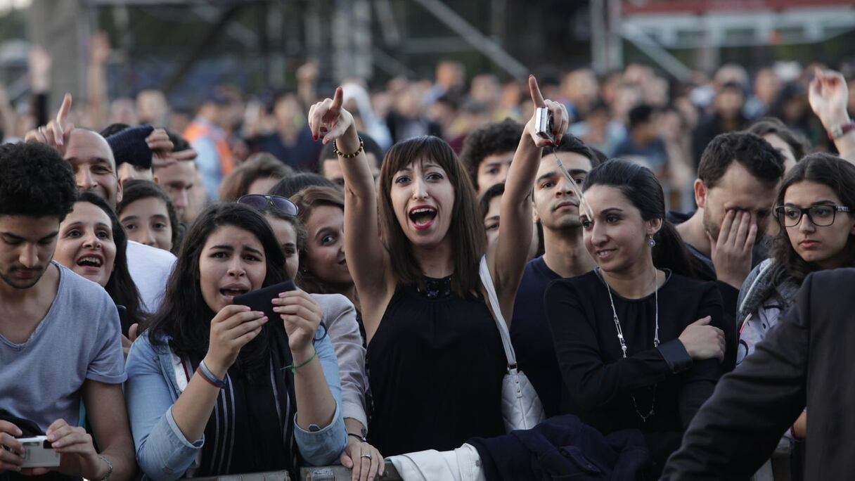 La lumière du jour s'atténue peu à peu. La foule, de visages souriants et déjà pleine d'entrain, prend de plus en plus d'ampleur. 
