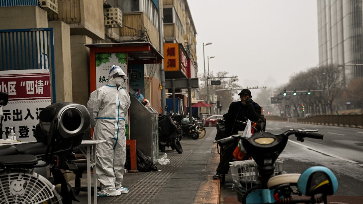 Un agent de santé surveille l'entrée d'une zone résidentielle dont les habitants ont été confinés, en raison de restriction liées au Covid-19, à Pékin, le 24 novembre 2022.
