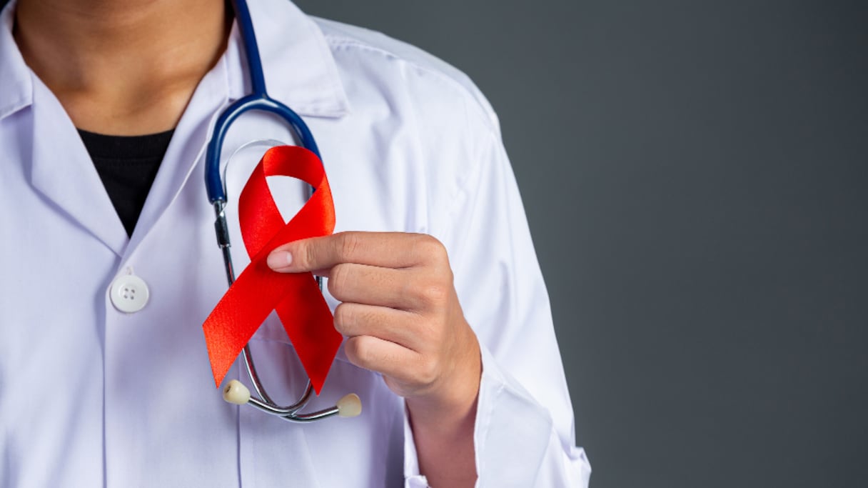 Une blouse blanche tient un ruban rouge, souvent porté en signe de solidarité avec les personnes qui vivent avec le VIH, et celles qui ont été emportées par le Sida.
