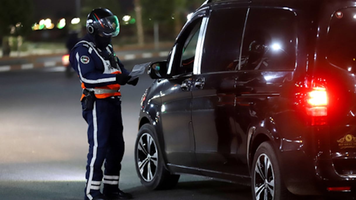 Un agent de la DGSN contrôle un conducteur, lors du couvre-feu nocturne, toujours en vigueur dans l'ensemble du Royaume. 
