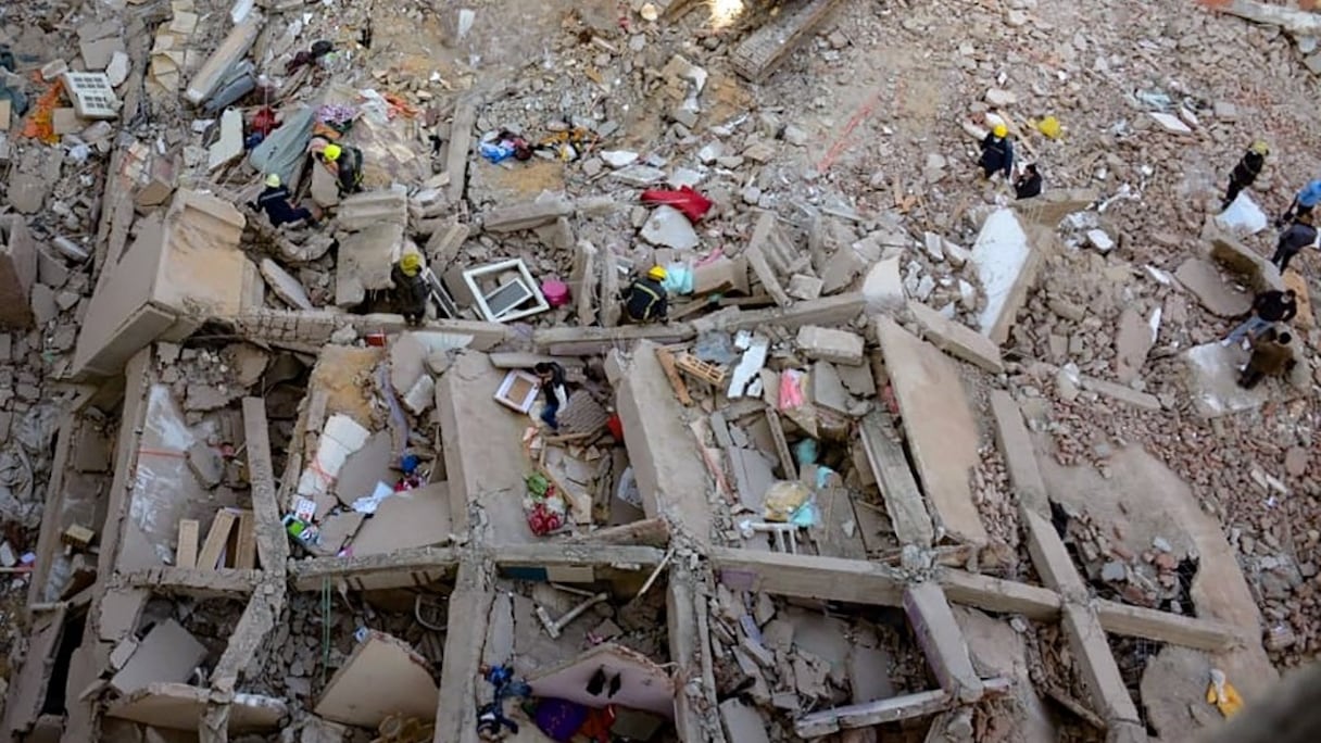 Des personnes et des sauveteurs se rassemblent autour des décombres d'un bâtiment qui s'est effondré dans le quartier populaire de Gesr Giza, à l'est de la capitale égyptienne, Le Caire, le 27 mars 2021.
