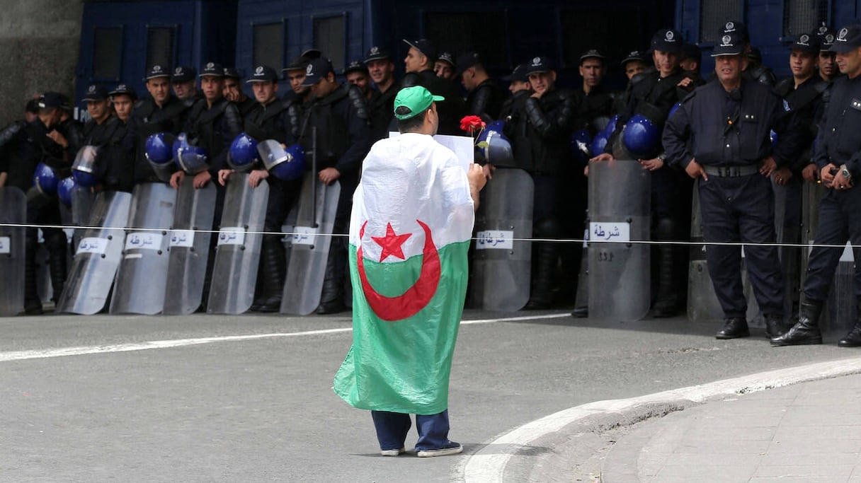 Un manifestant couvert du drapeau algérien fait face aux forces de l'ordre à Alger, le 24 mai 2019.
