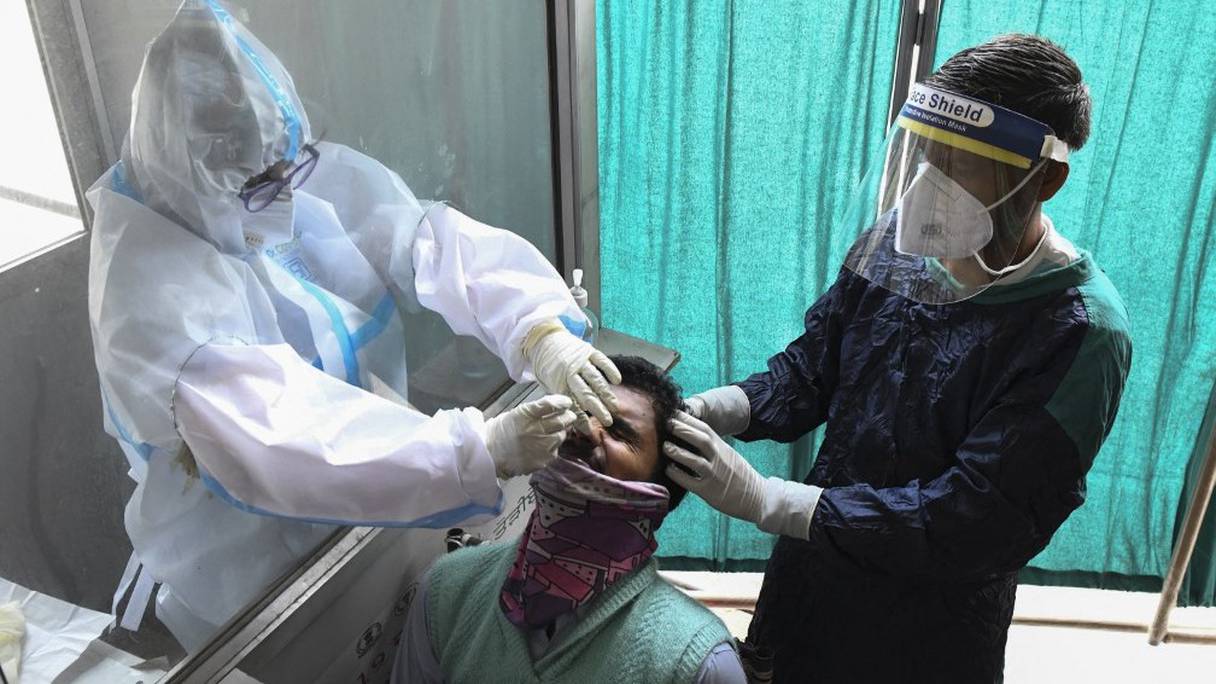 Un agent de santé prélève un échantillon sur écouvillon nasal d'un homme pour tester le coronavirus Covid-19 à Amritsar, en Inde, le 21 avril 2021.
