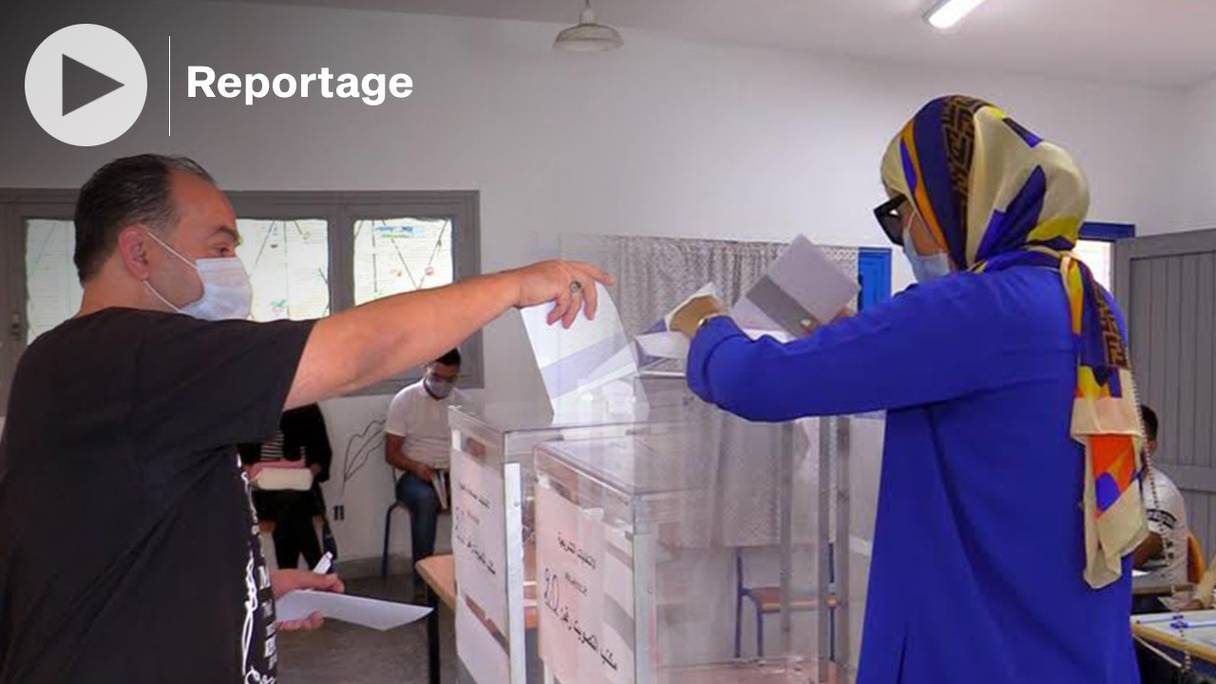 Des électeurs glissent leur bulletin de vote dans l'urne et s'acquittent de leur devoir électoral, lors des scrutins législatifs, régionaux et municipaux du 8 septembre 2021, à l'école Abderrahmane Anegay, dans le centre-ville de Tanger. 
