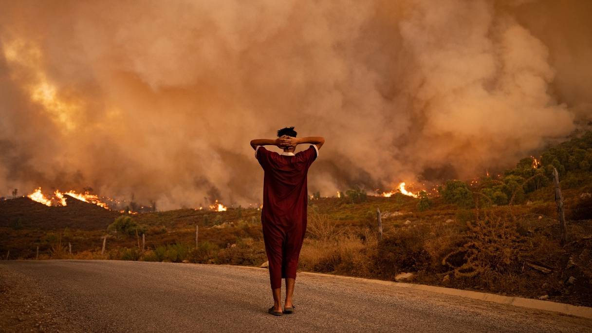 Une femme regarde les flammes ravager une forêt de la région de Chefchaouen, dans le nord du Royaume, le 15 août 2021.
