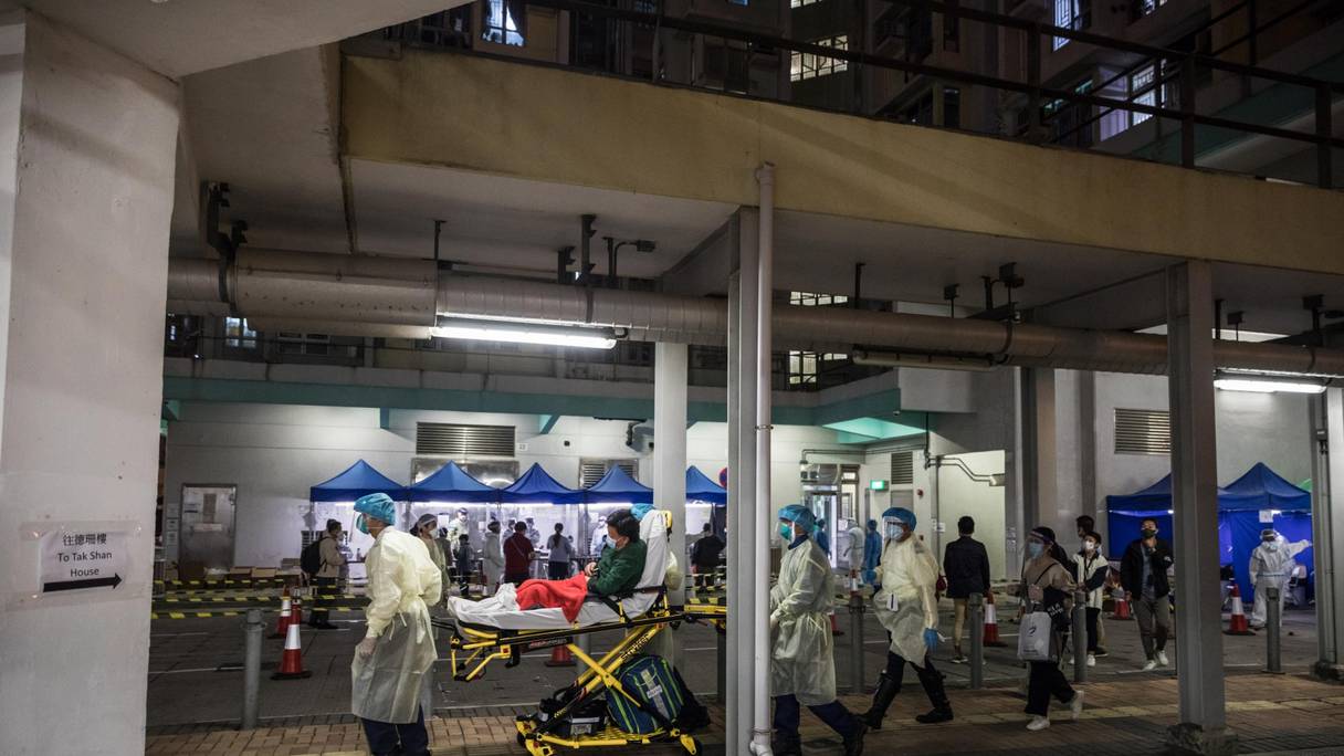 Des agents de santé déplacent un homme sur une civière dans un immeuble verrouillé pendant que les résidents sont testés pour Covid-19 après que les échantillons d'eaux usées de l'immeuble ont été testés positifs, à Hong Kong le 4 mars 2022.
