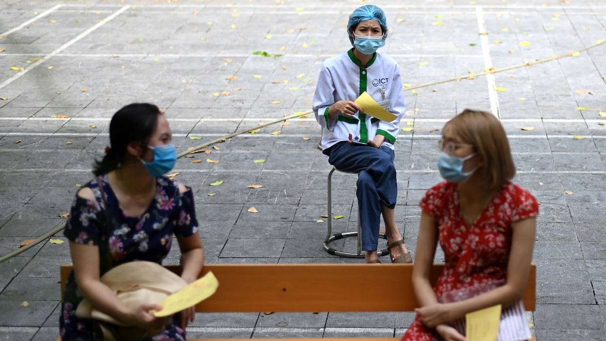 Distanciation sociale entre personnes, en attendant de recevoir le vaccin contre le coronavirus AstraZeneca Covid-19 à l'école secondaire Trung Vuong de Hanoï, au Vietnam, le 30 juillet 2021.
