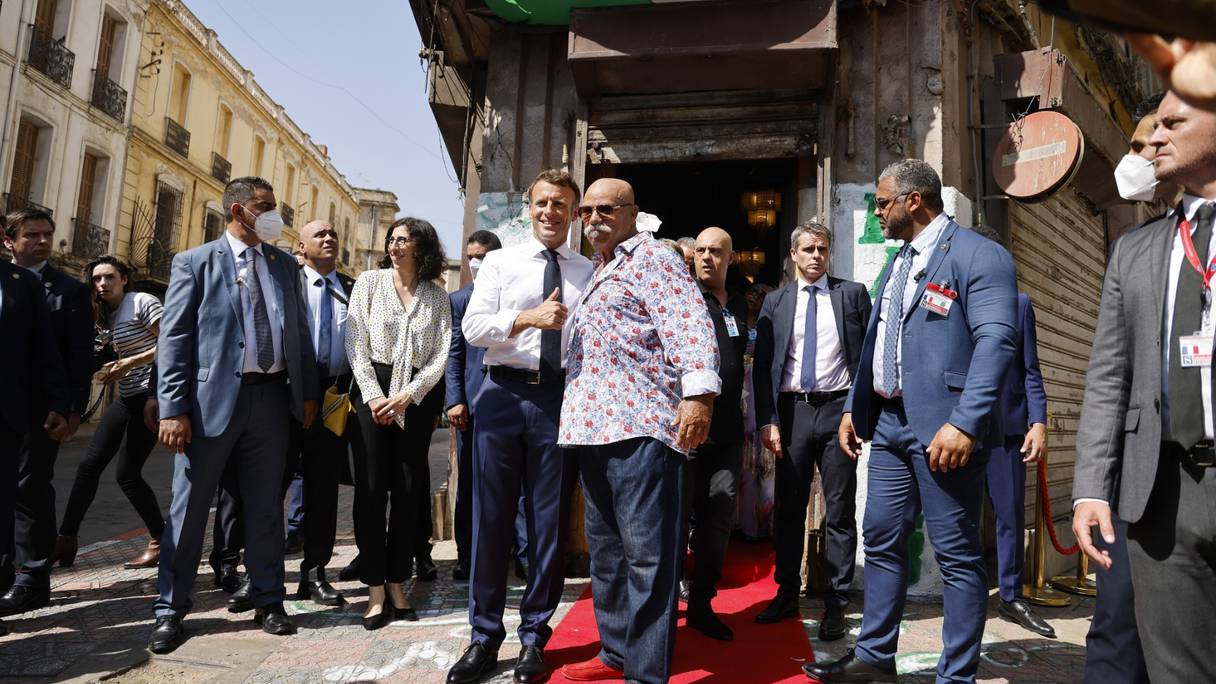 Le président français prenant la pose avec le propriétaire du label raï Disco Maghreb, samedi 27 août 2022, à Oran, en Algérie.
