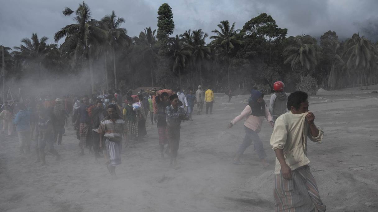 Des villageois récupèrent leurs biens dans une zone couverte de cendres volcaniques dans le village de Sumber Wuluh à Lumajang, à l'est de l'île de Java, le 5 décembre 2021, après l'éruption du volcan Semeru qui a tué au moins 13 personnes.
