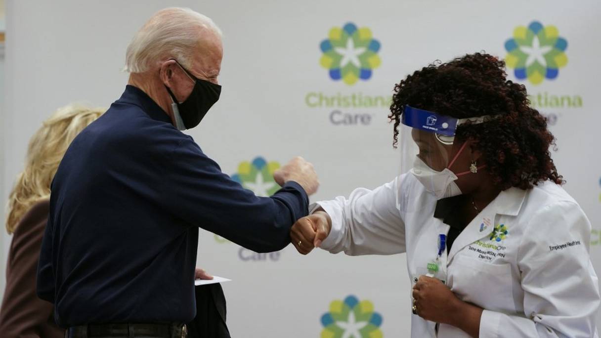 Le président élu Joe Biden salue Tabe Mase, l'infirmière qui lui a injecté une première dose du vaccin développé par Pfizer BionTech dans un centre médical de Newark (Delaware), le 21 décembre 2020. 
