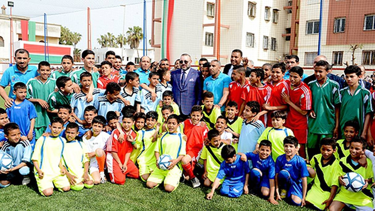 Le souverain entouré de jeunes lors de l'inauguration du stade de proximité ce 30 mars à Casablanca.
