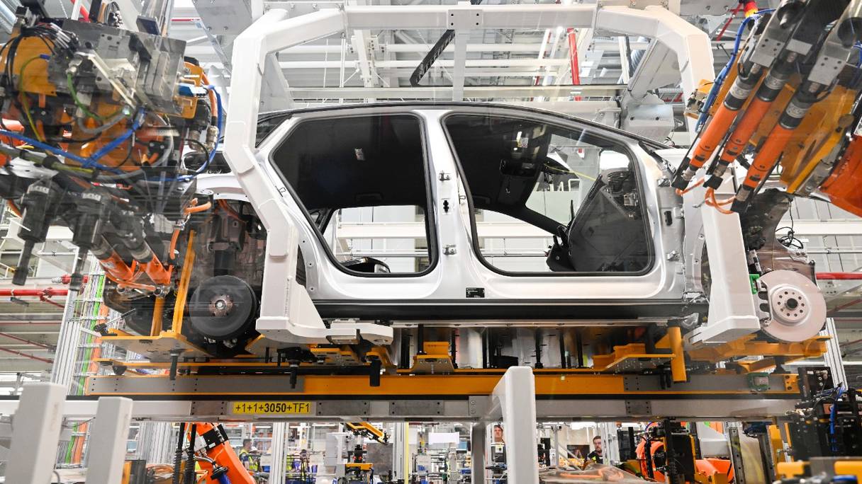 Des robots travaillent sur la chaîne de montage d'une voiture électrique Volkswagen ID.4, au cours du lancement de sa production sur le site du constructeur automobile allemand Volkswagen à Emden, dans le nord de l'Allemagne, le 20 mai 2022.
